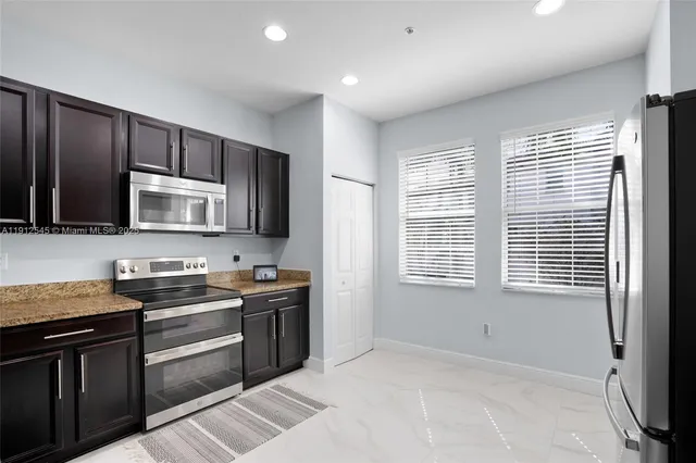 a kitchen with stainless steel appliances granite countertop a stove a sink and a microwave