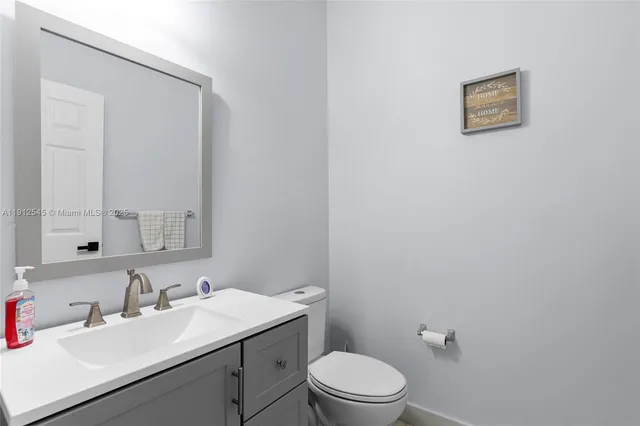 a bathroom with a toilet sink vanity and mirror