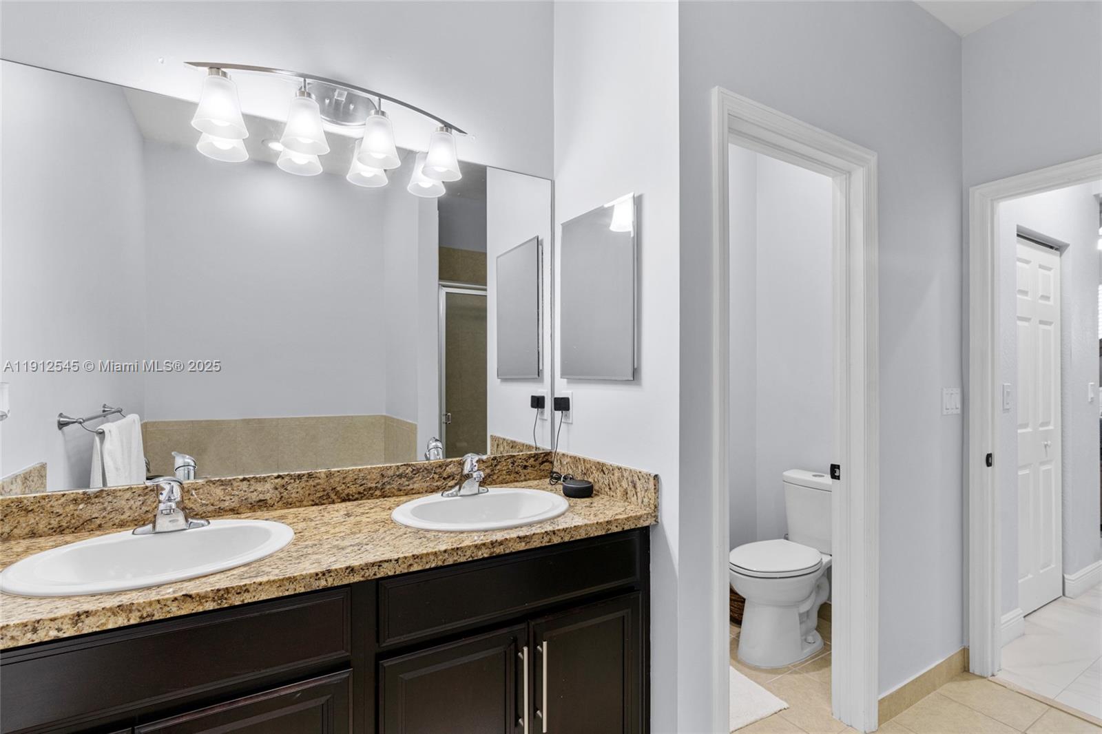 2565 Southwest 119th Terrace Miramar, FL 33025 - Photo 24 of 37 a bathroom with a granite countertop sink a toilet and a mirror