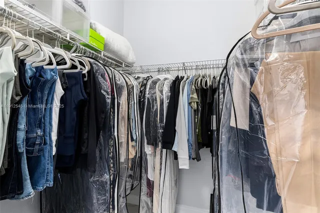 a view of walk in closet with clothes and shoes
