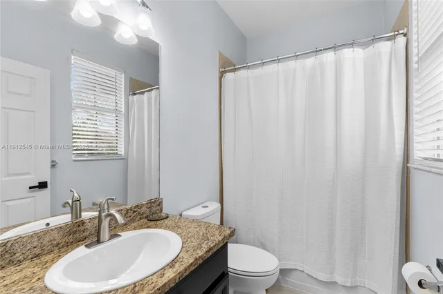 a bathroom with a granite countertop sink toilet and shower