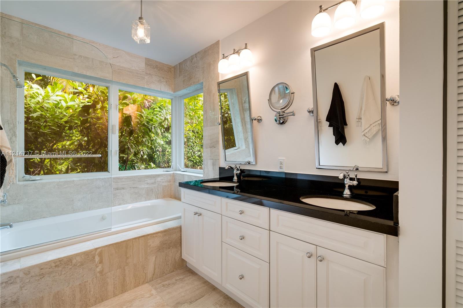 3731 Battersea Road Miami, FL 33133 - Photo 19 of 44 a bathroom with a double vanity sink and a bathtub