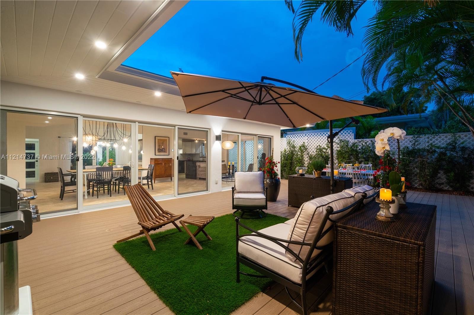 3731 Battersea Road Miami, FL 33133 - Photo 25 of 44 a view of a patio with a dining table and chairs under an umbrella