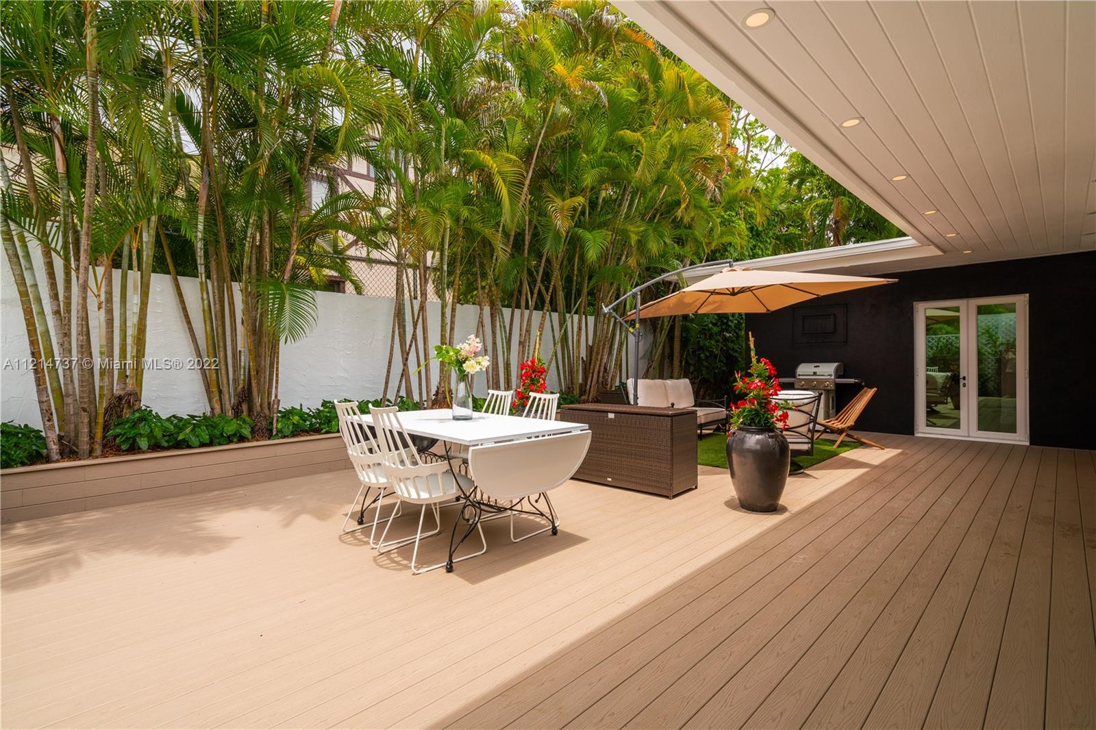 3731 Battersea Road Miami, FL 33133 - Photo 29 of 44 a view of a patio with table and chairs under an umbrella with wooden floor