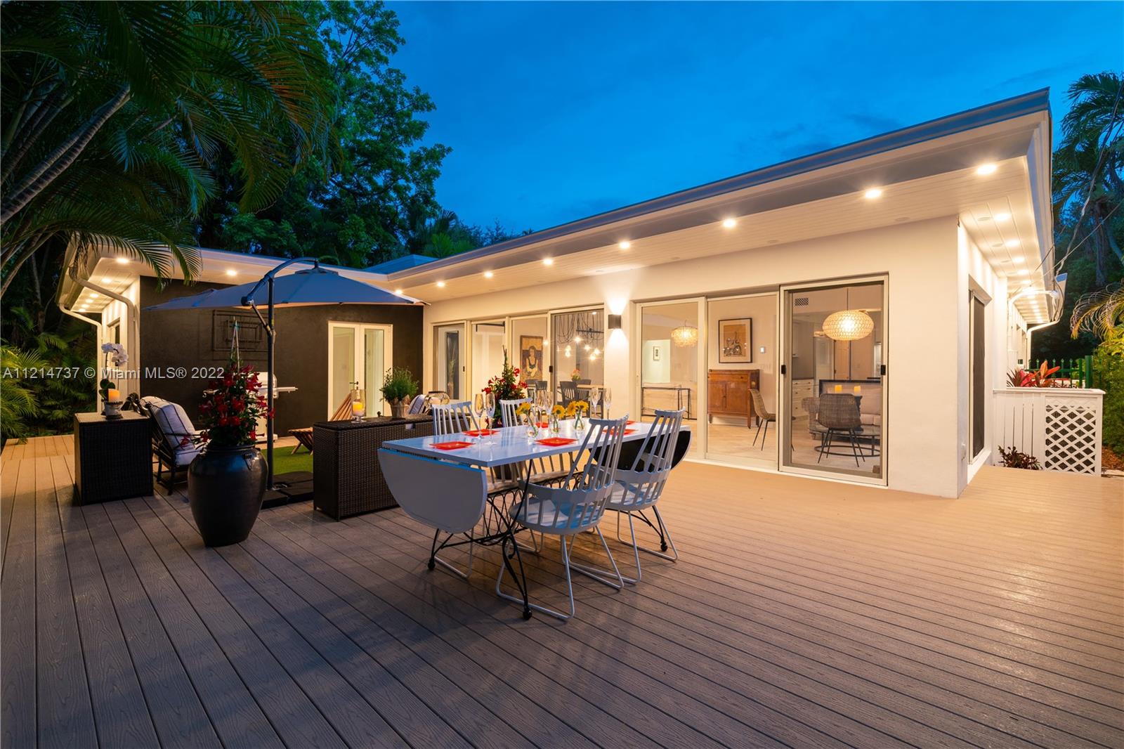 3731 Battersea Road Miami, FL 33133 - Photo 39 of 44 a view of a patio with table and chairs potted plants with wooden floor and fence