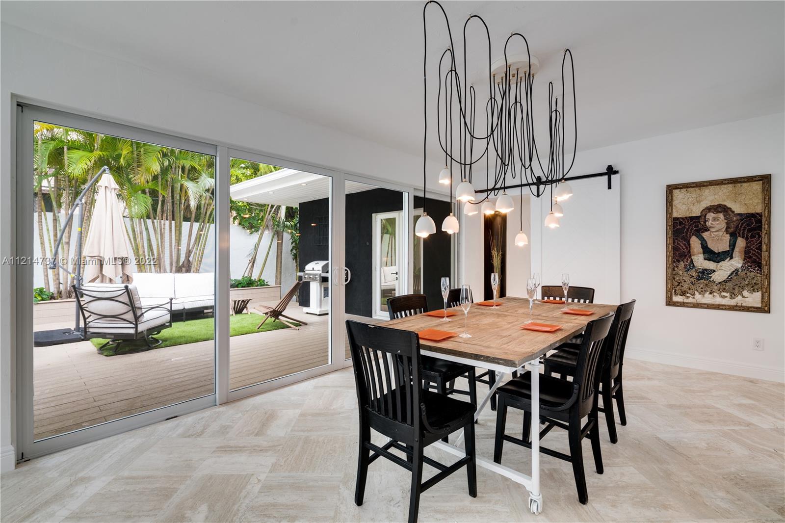 3731 Battersea Road Miami, FL 33133 - Photo 41 of 44 a dining room with furniture a rug a potted plant and a chandelier