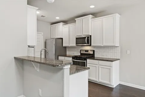 a kitchen with stainless steel appliances granite countertop a sink a stove a refrigerator a microwave and cabinets