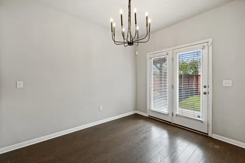 a view of a room with wooden floor chandelier and windows