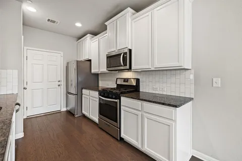 a kitchen with stainless steel appliances granite countertop a stove a sink and a refrigerator