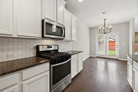 a kitchen with stainless steel appliances granite countertop a stove a microwave and a white cabinets