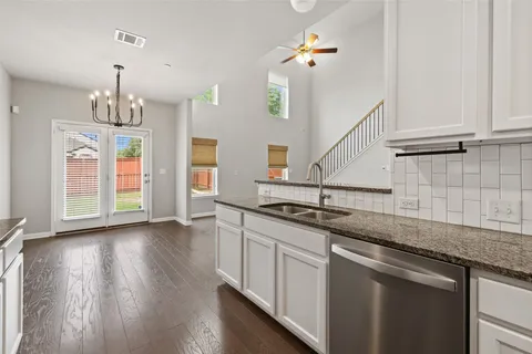 a kitchen with granite countertop a sink a counter space and cabinets