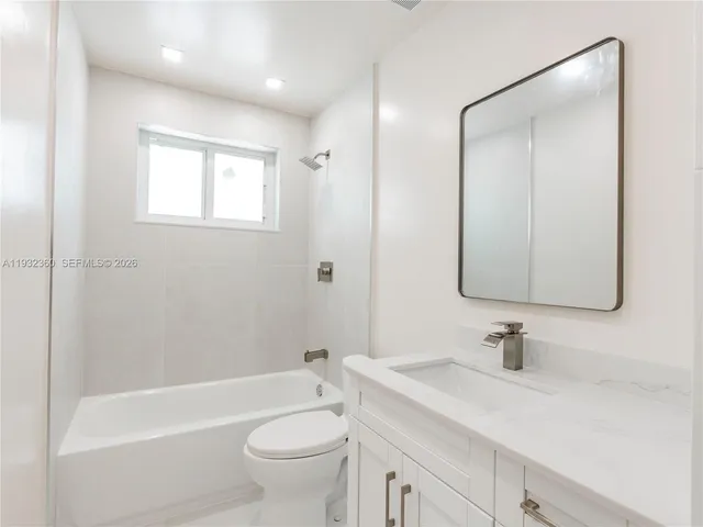a bathroom with a granite countertop sink a toilet and shower