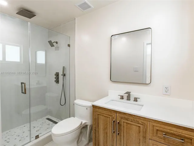a bathroom with a granite countertop sink a toilet and shower