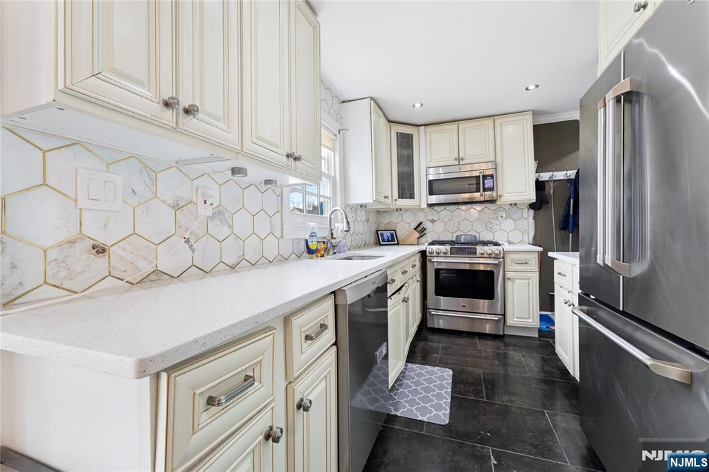 74 Spring Avenue Bergenfield, NJ 07621 - Photo 11 of 39 a kitchen with white cabinets and stainless steel appliances