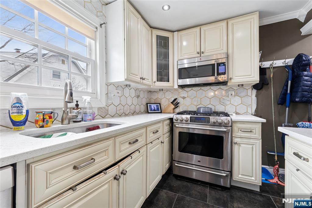 74 Spring Avenue Bergenfield, NJ 07621 - Photo 12 of 39 a kitchen with stainless steel appliances granite countertop grey cabinets a stove a sink and a refrigerator