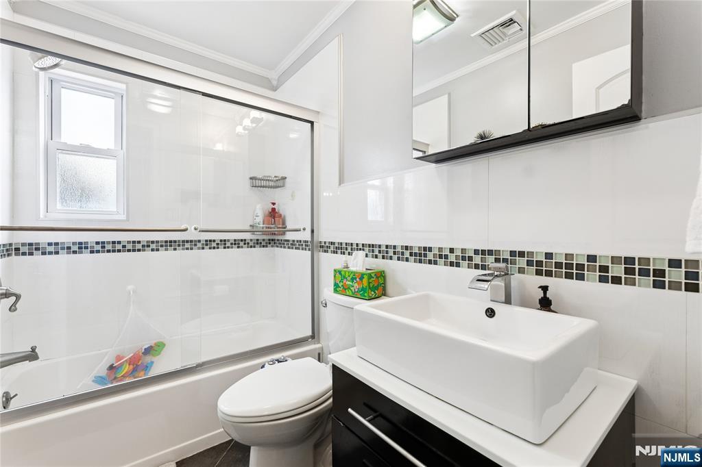 74 Spring Avenue Bergenfield, NJ 07621 - Photo 15 of 39 a bathroom with a sink a toilet and a mirror