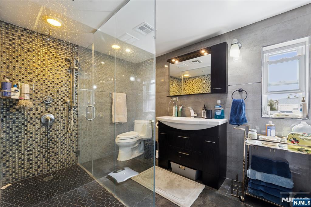 74 Spring Avenue Bergenfield, NJ 07621 - Photo 21 of 39 a bathroom with a sink toilet a mirror and shower