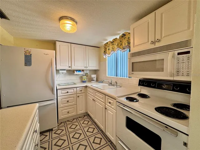 a kitchen with a white stove top oven and white countertops with wooden floor