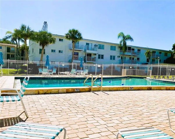 a view of swimming pool with lawn chairs and plants