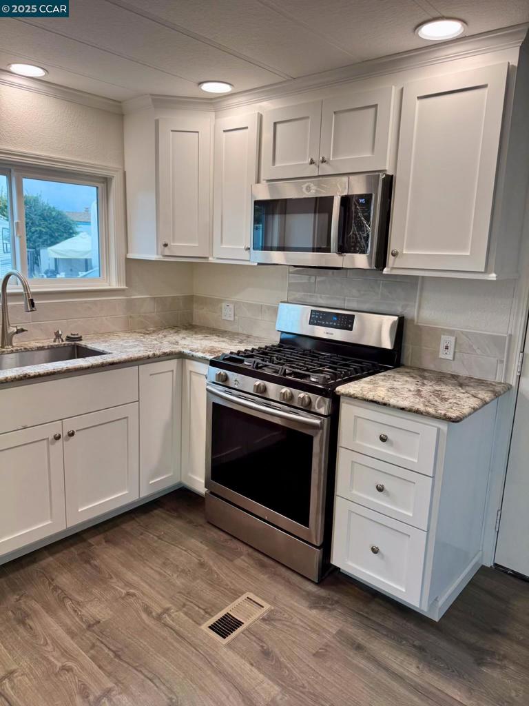 747 Lewelling Boulevard San Leandro, CA 94579 - Photo 9 of 14 a kitchen with cabinets stainless steel appliances a sink and wooden floor