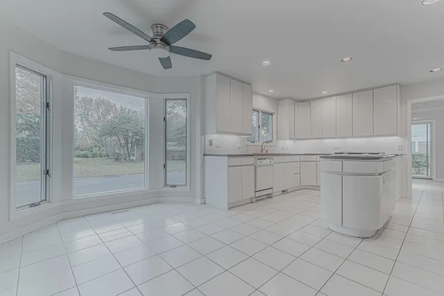 a kitchen with white cabinets a sink a stove a refrigerator and island