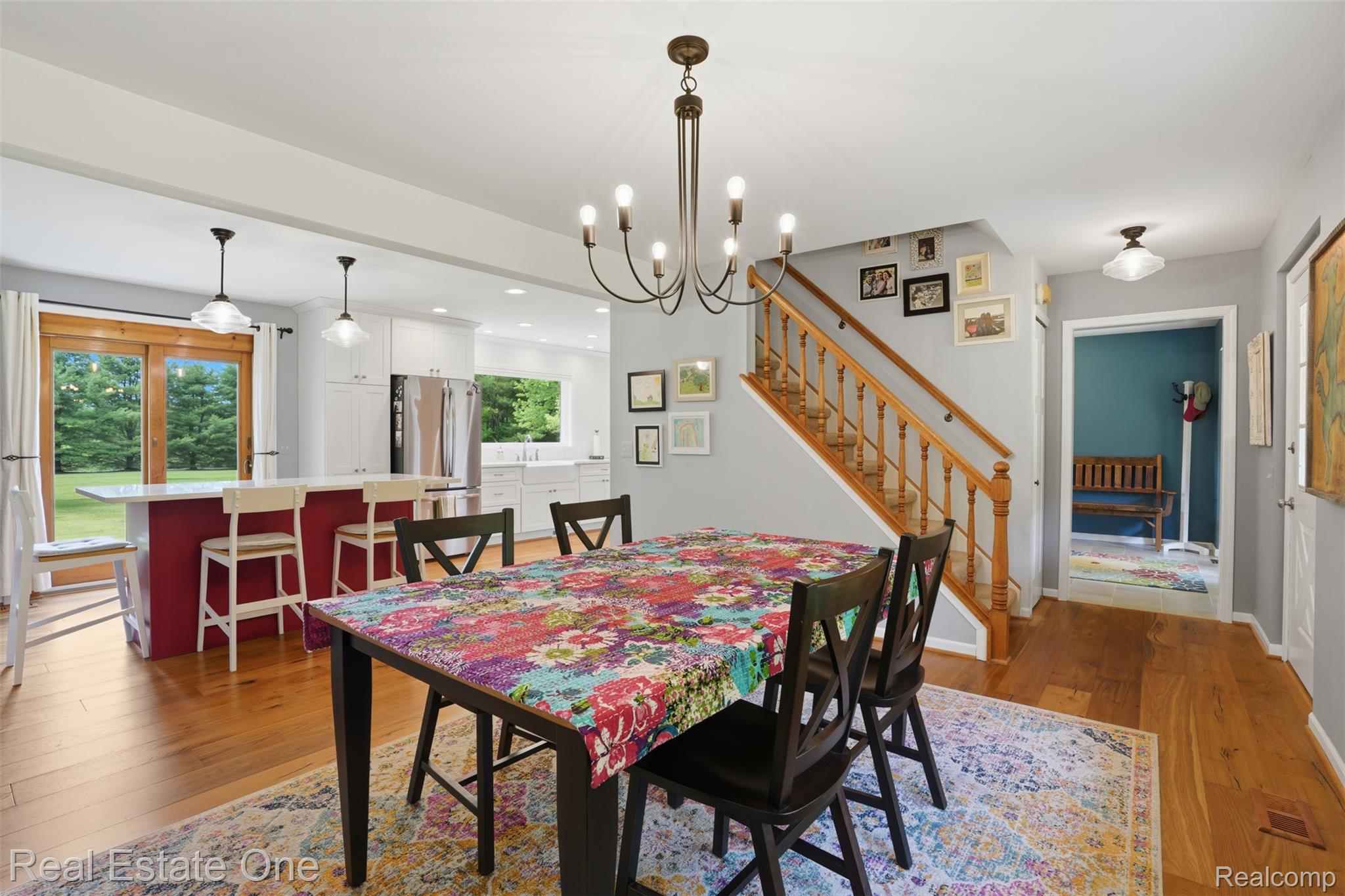 1765 Rowe Road Milford, MI 48380 - Photo 8 of 61 Open-concept dining area featuring wood-finish flooring, a contemporary chandelier, and a wood staircase with balusters
