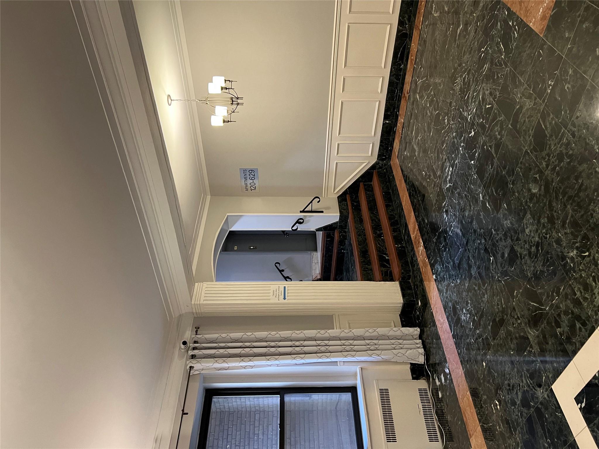 35-35 75th Street, Unit 127 Queens, NY 11372 - Photo 12 of 50 Unfurnished room with crown molding, radiator heating unit, and an inviting chandelier