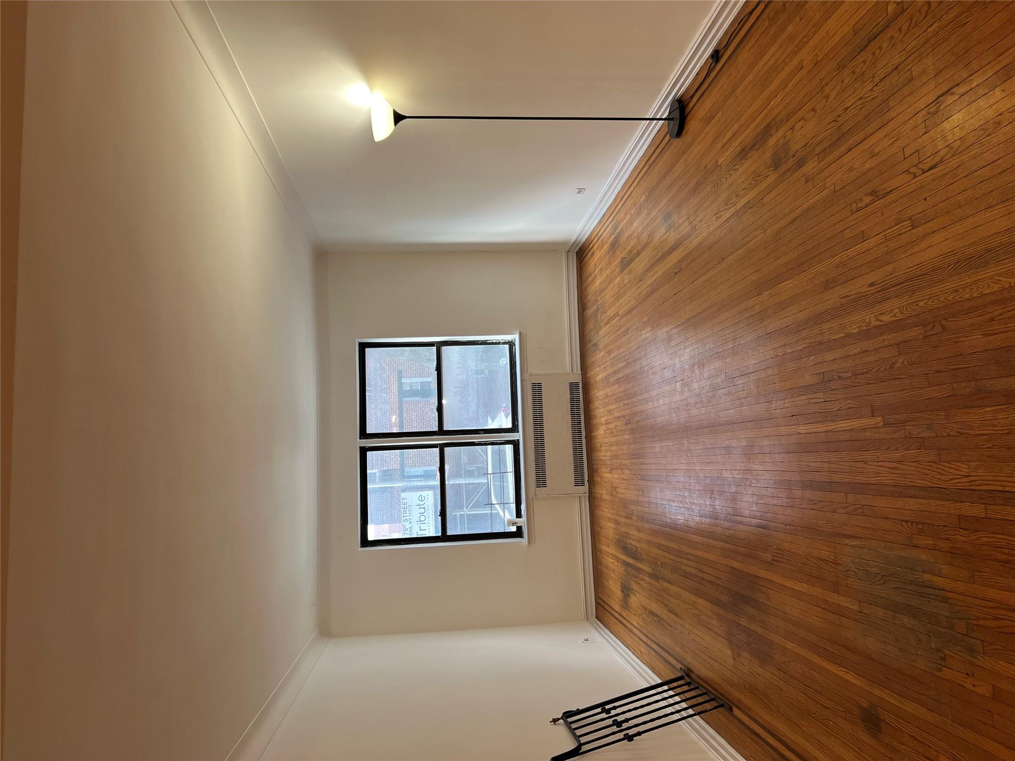 35-35 75th Street, Unit 127 Queens, NY 11372 - Photo 17 of 50 Empty room with radiator, wood-type flooring, and ornamental molding