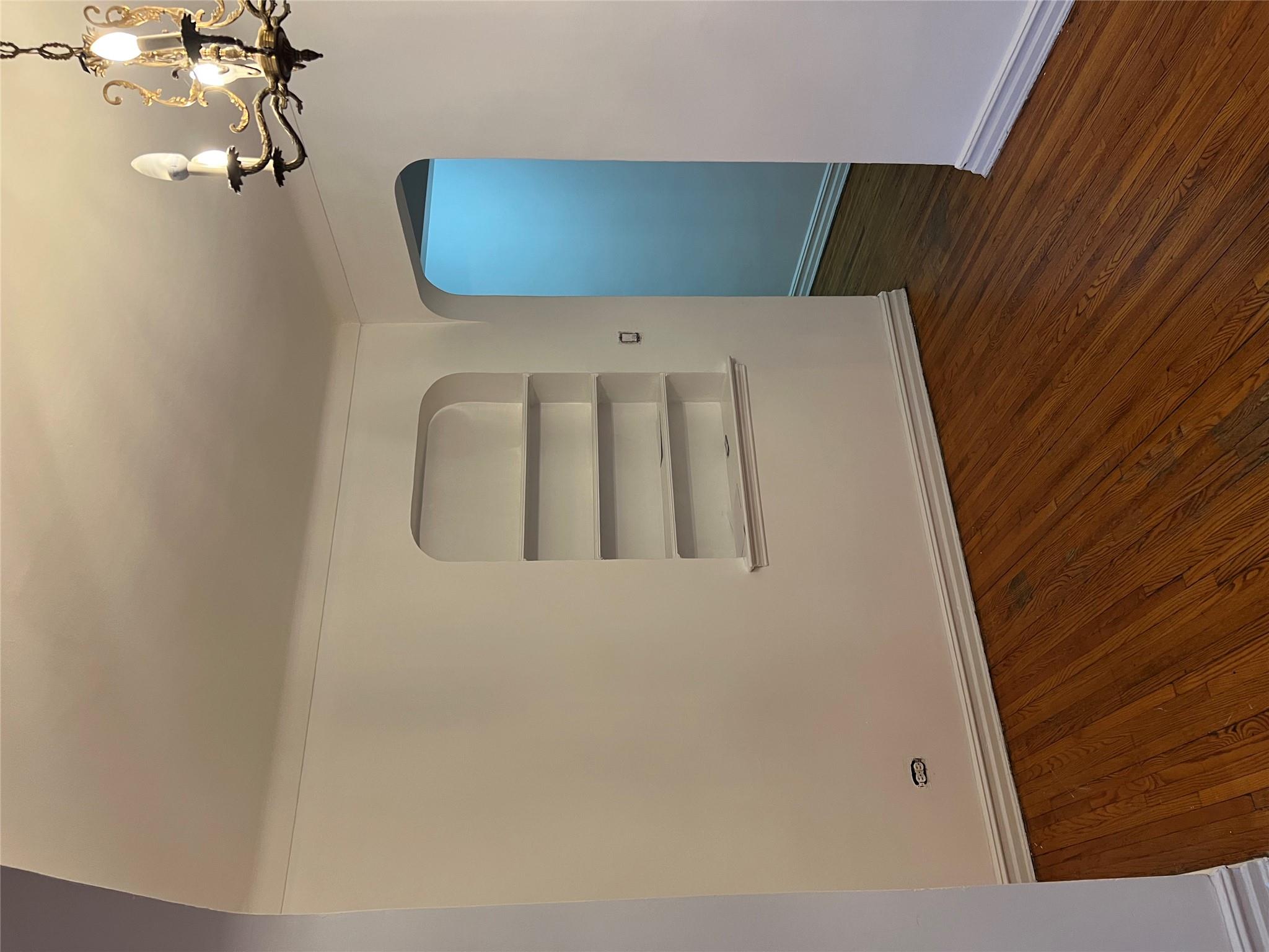 35-35 75th Street, Unit 127 Queens, NY 11372 - Photo 19 of 50 Spare room featuring dark hardwood / wood-style flooring, built in features, and a notable chandelier