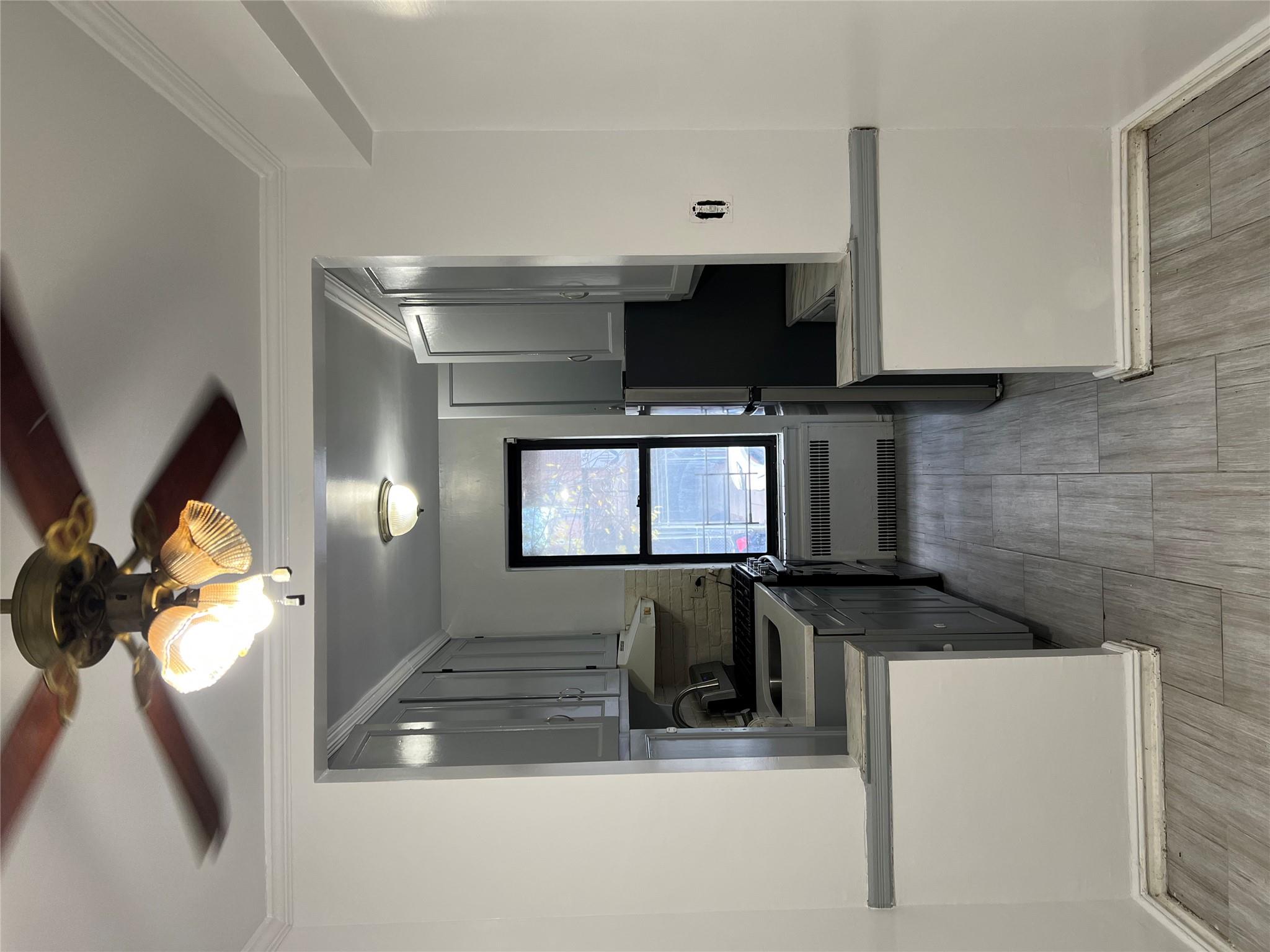 35-35 75th Street, Unit 127 Queens, NY 11372 - Photo 22 of 50 Kitchen with gray cabinetry, radiator, crown molding, ceiling fan, and tasteful backsplash