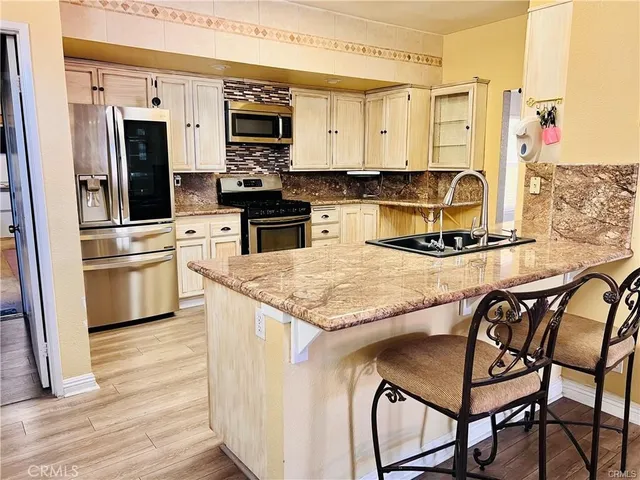 a kitchen with granite countertop kitchen island stainless steel appliances and wooden cabinets