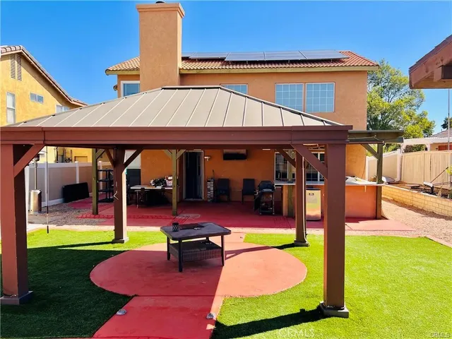 a patio with table and chairs with a barbeque grill