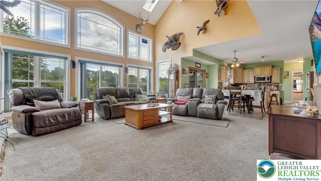 a living room with furniture a fireplace and floor to ceiling windows