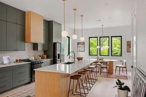 a kitchen with stainless steel appliances kitchen island granite countertop a table chairs in it and a wooden floors