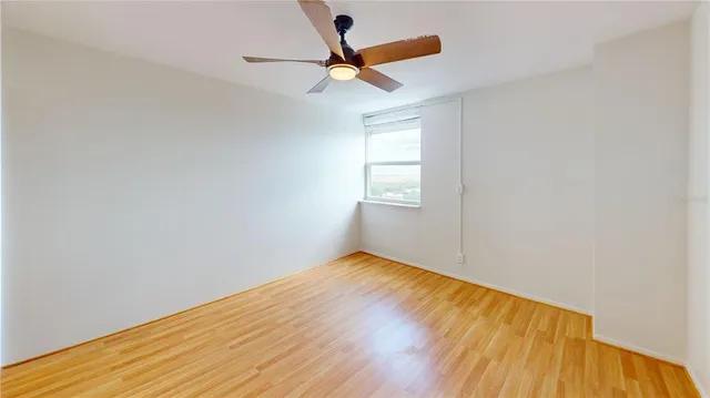 an empty room with a window and a ceiling fan