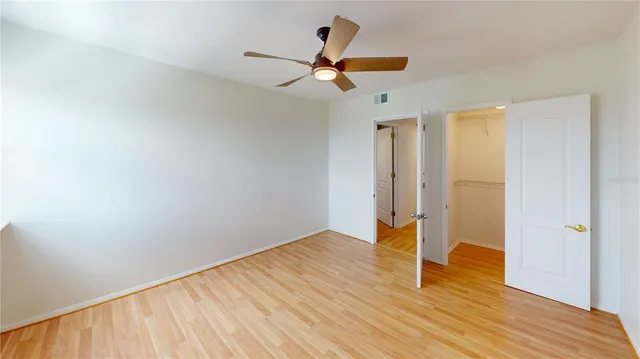 a view of a big room with wooden floor closet and ceiling fan