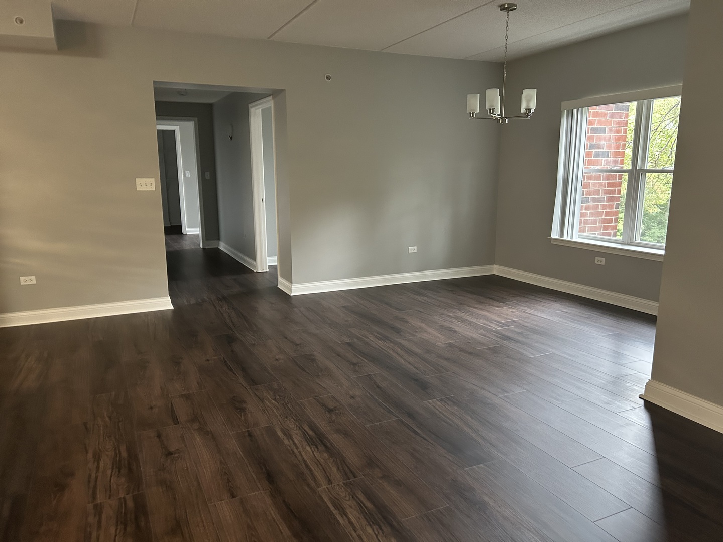 3400 North Old Arlington Heights Road, Unit 306 Arlington Heights, IL 60004 - Photo 3 of 10 an empty room with wooden floor chandelier and windows