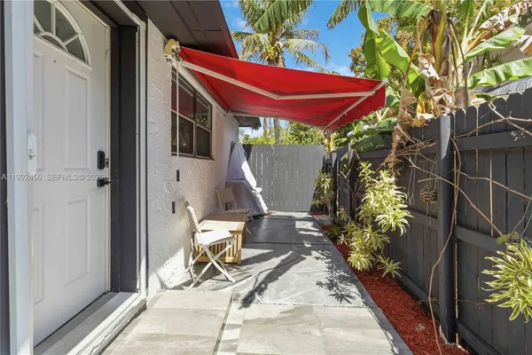 a patio with table and chairs and potted plants