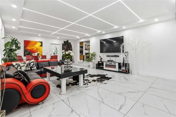 a living room with furniture a flat screen tv and a floor to ceiling window