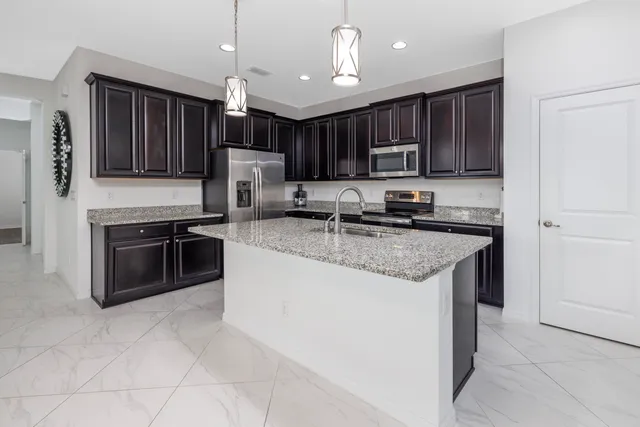 a kitchen with kitchen island granite countertop a stove a sink a microwave a dining table and chairs with wooden floor