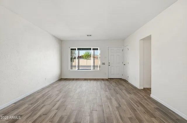 an empty room with wooden floor and windows