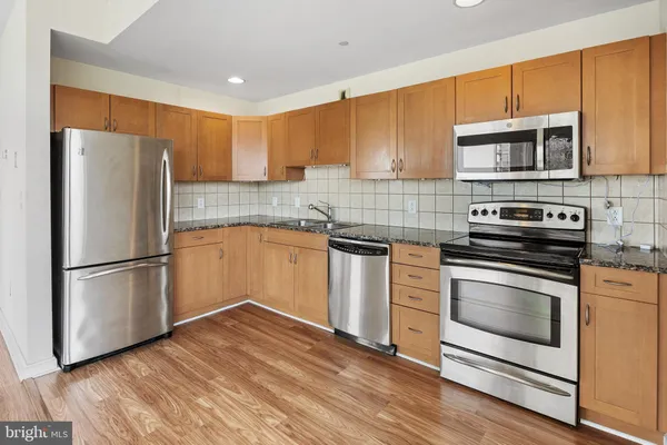 a kitchen with stainless steel appliances granite countertop a refrigerator stove a sink and a microwave