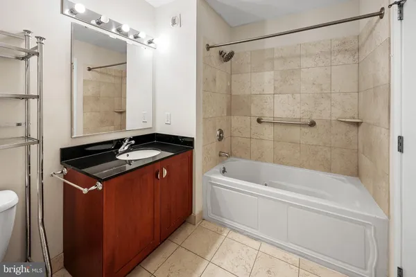 a bathroom with a granite countertop sink a toilet mirror and shower