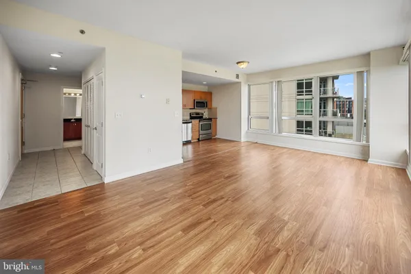 a view of an empty room with wooden floor and a window