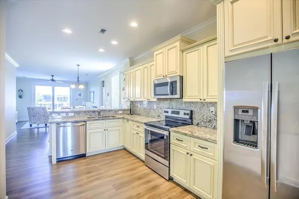 a kitchen with stainless steel appliances granite countertop hardwood floor sink stove and white cabinets