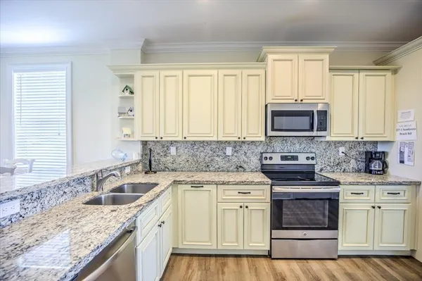 a kitchen with granite countertop white cabinets sink and stainless steel appliances