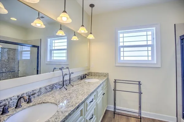 a bathroom with a granite countertop sink a large mirror and a shower