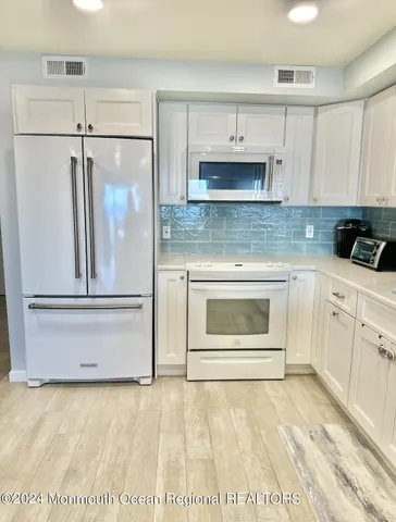 a kitchen with white cabinets and white appliances