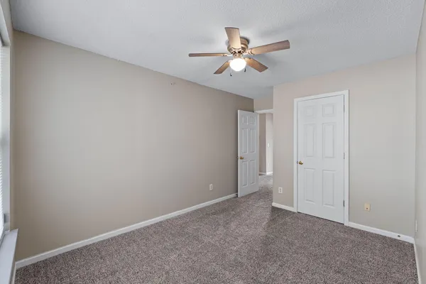 a view of an empty room and chandelier fan
