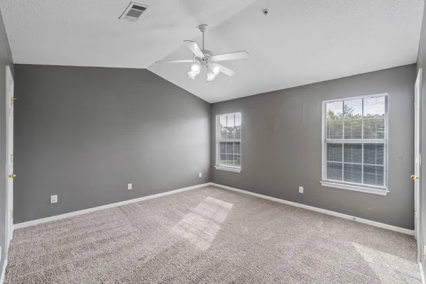 an empty room with windows and fan